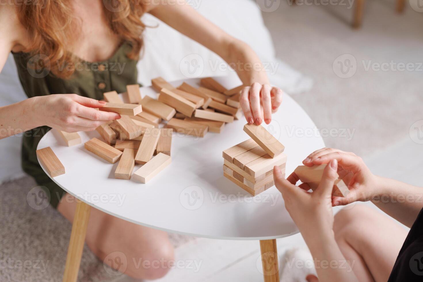 two women playing a board game made of wooden blocks at home, excitement and relaxation, mind development concept, hand motor skills, photo