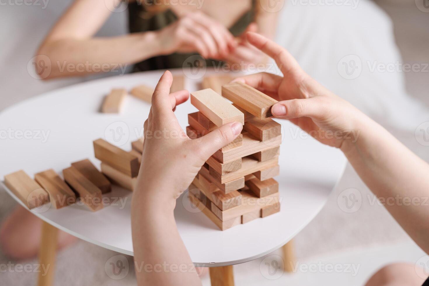 two women playing a board game made of wooden blocks at home, excitement and relaxation, mind development concept, hand motor skills, photo
