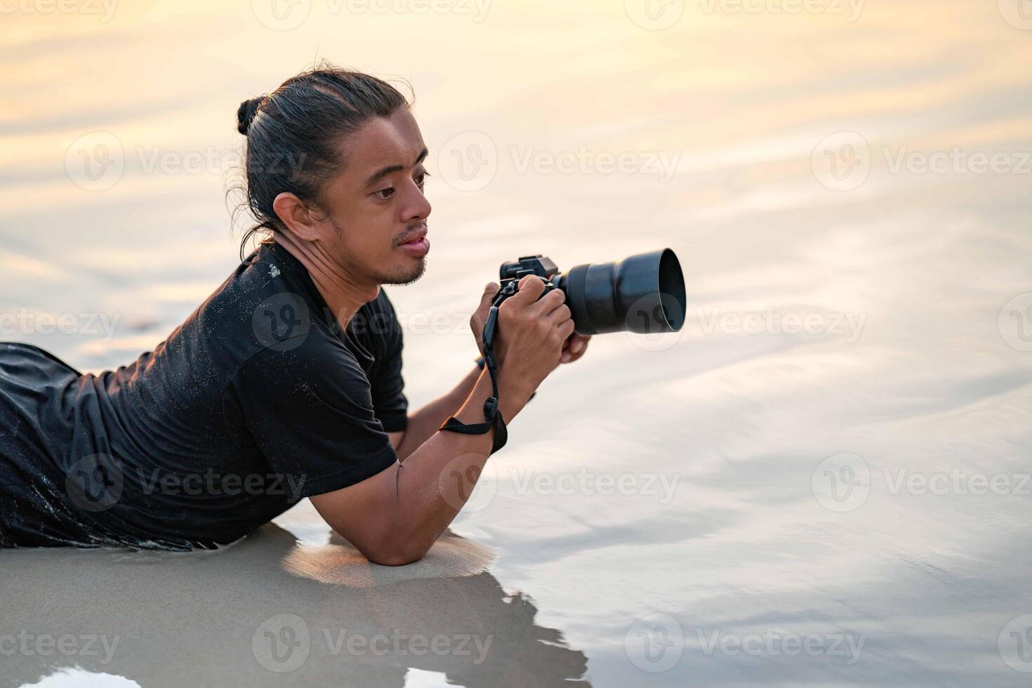 Male Photographer lays on the beach with the sunset light from behind him at Phuket Province, Thailand. photo