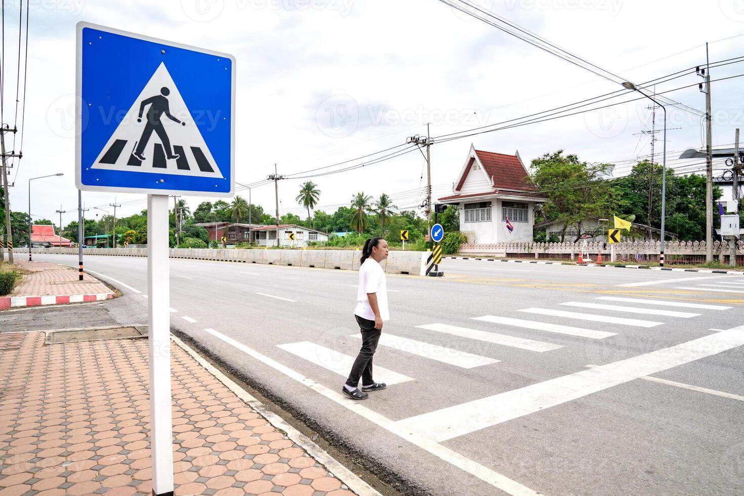 Asian man looks to vehicle on the road, he waits for sure to across crosswalk to the other side, Thailand. photo