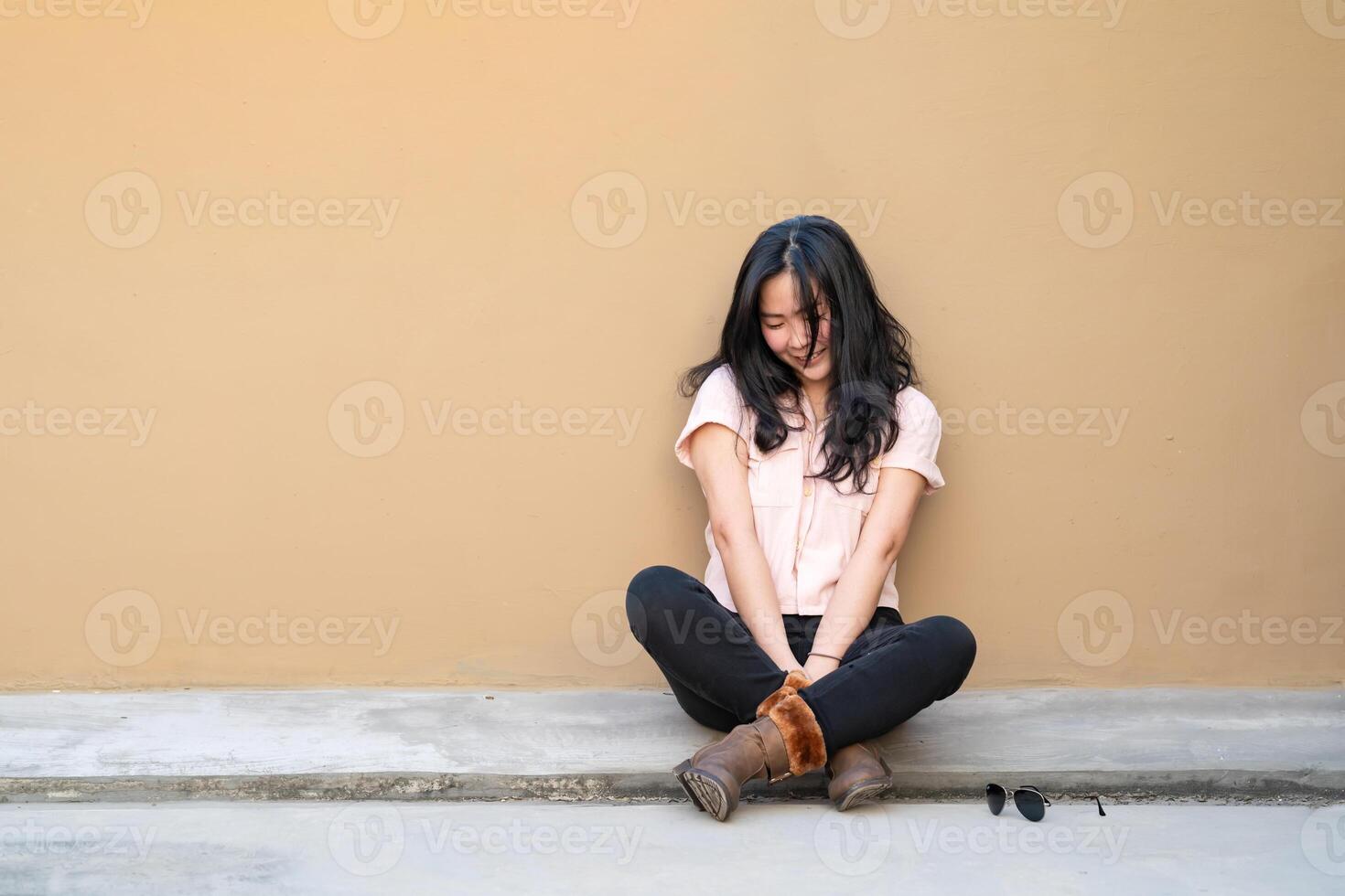 The Asian woman is sitting, crying and smiling alone at the same time on the rooftop of the building. This is not a good day for her. photo