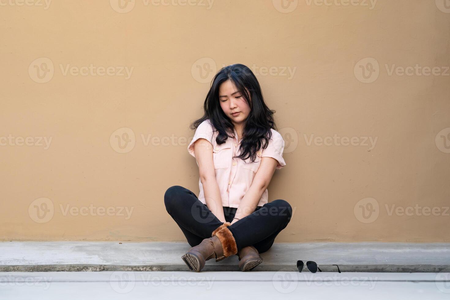 Asian woman is sitting alone on the rooftop of building with tried and disappointed mood and tone in that day. photo