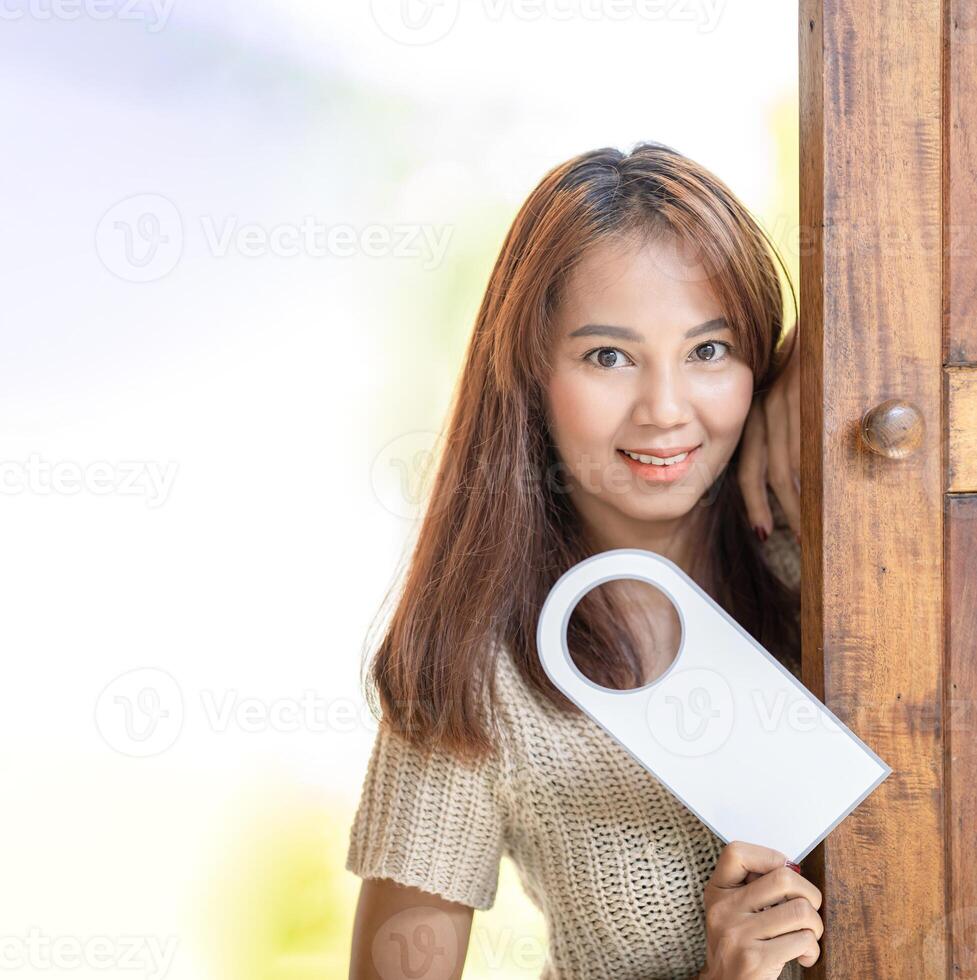 Asian Cute woman hold door tag and smile in front of wood door at outdoor field. photo
