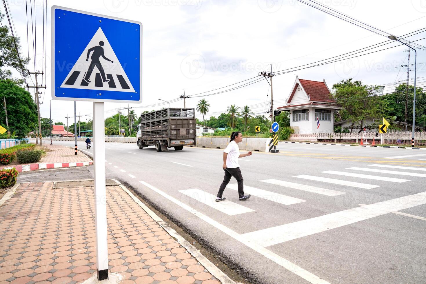 An Asian man prepares himself to walk and run across crosswalk to the other side, Thailand. photo