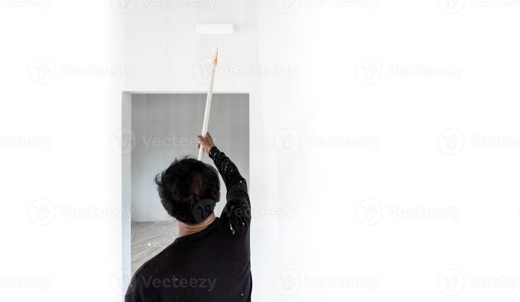 professional worker man is rolling and painting interior white wall. photo