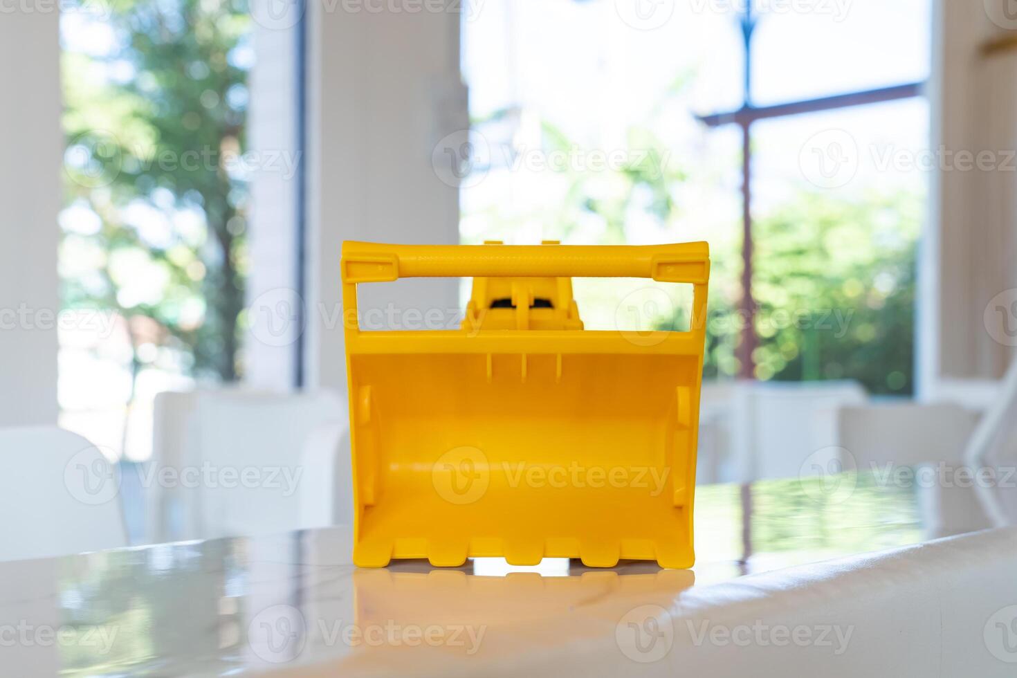 A yellow construction Loader toy vehicle with articulated parts built with sturdy plastic is placed on a table. photo