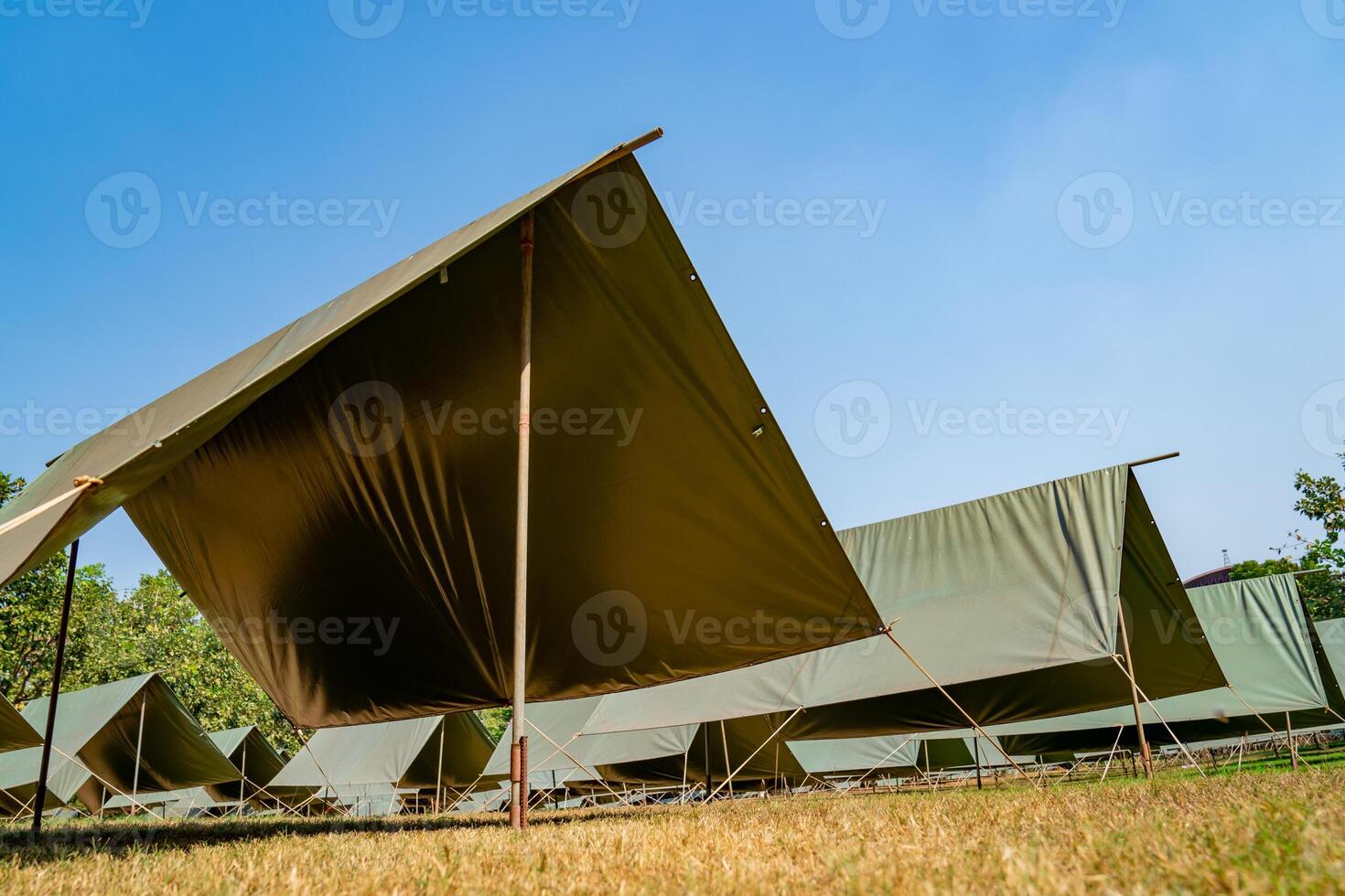 The simple and normal empty Canvas Tents in the row and column on the grass field at outdoor field in afternoon time. photo