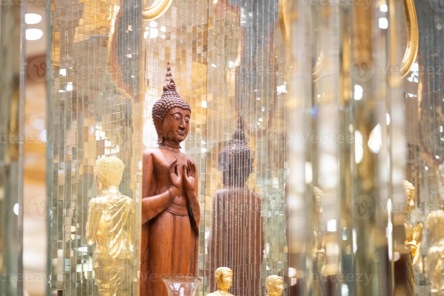 standing Buddha statue made of wood was placed between the smaller golden Buddha images of apostles. photo