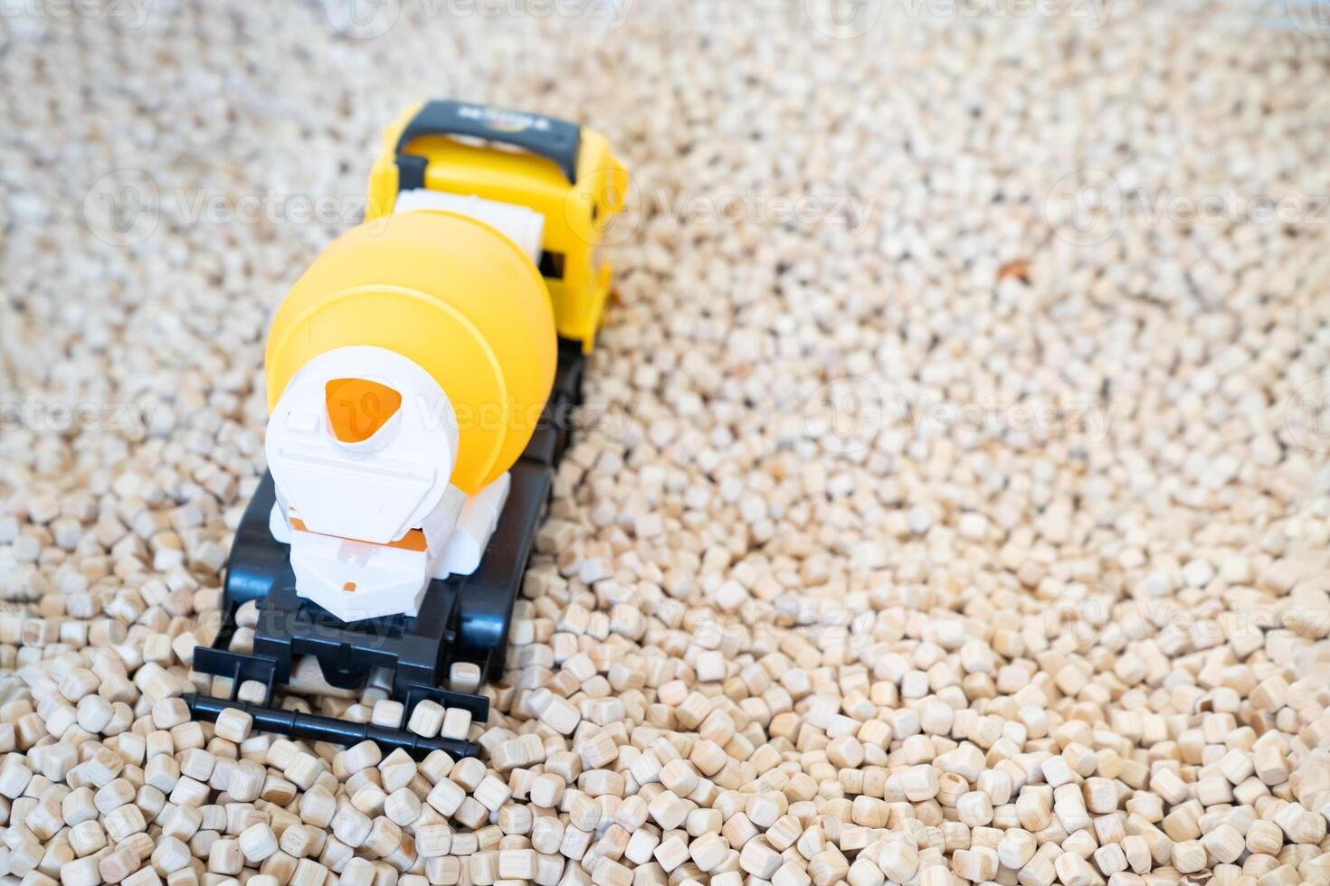 A kid is playing with a yellow plastic concrete mixer truck toy in the cork pool. photo