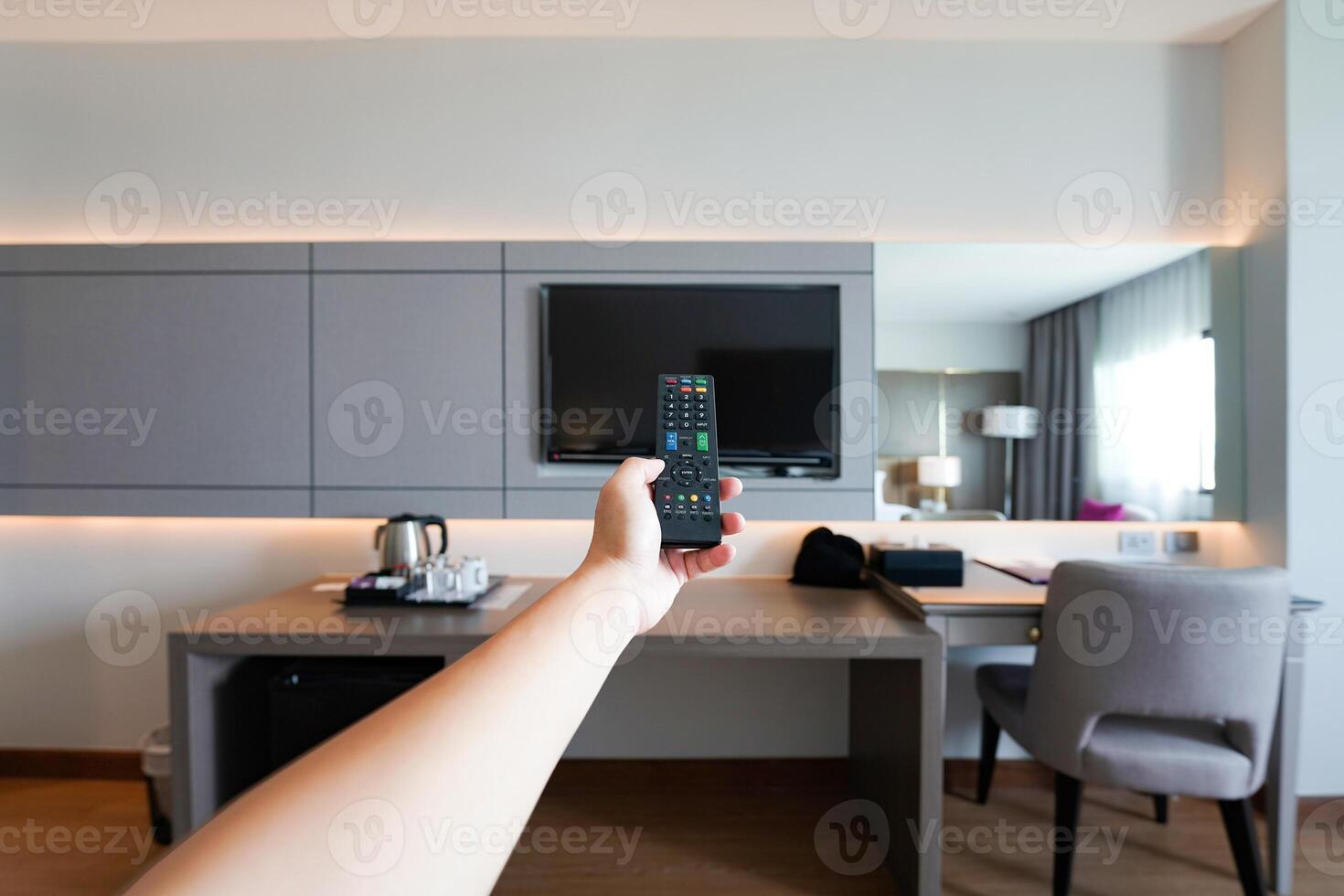 Watching TV using dust remote controller in the man's hand with resort hotel room blur the background at Nakhon Phanom Province, Thailand. photo
