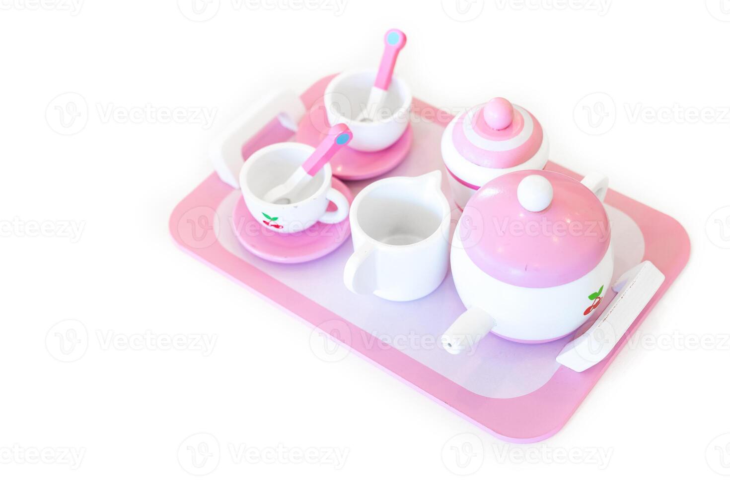 A set of pink white pastel color wood toy tea cups including 2 coffee cups with teaspoons, a teapot, a sugar jar and a milk jug is placed on a tray. Isolate clear on white background. photo