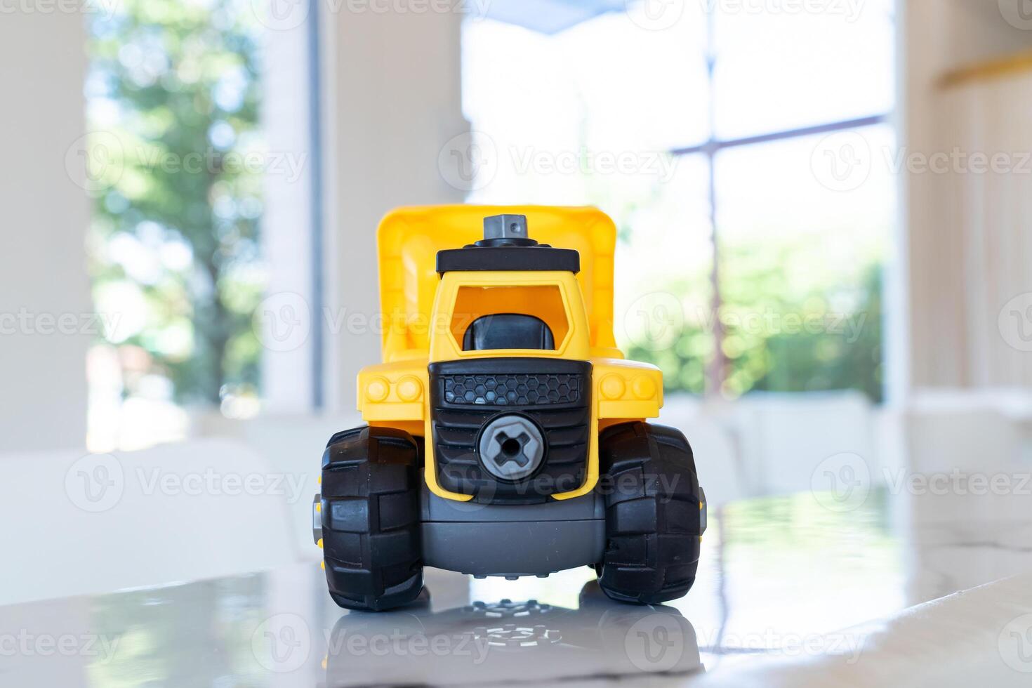 Dump truck, yellow construction toy vehicle with articulated parts built with sturdy plastic is placed on a table. photo