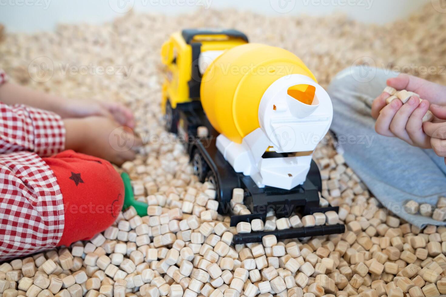 A kid is playing with a yellow plastic concrete mixer truck toy in the cork pool. photo