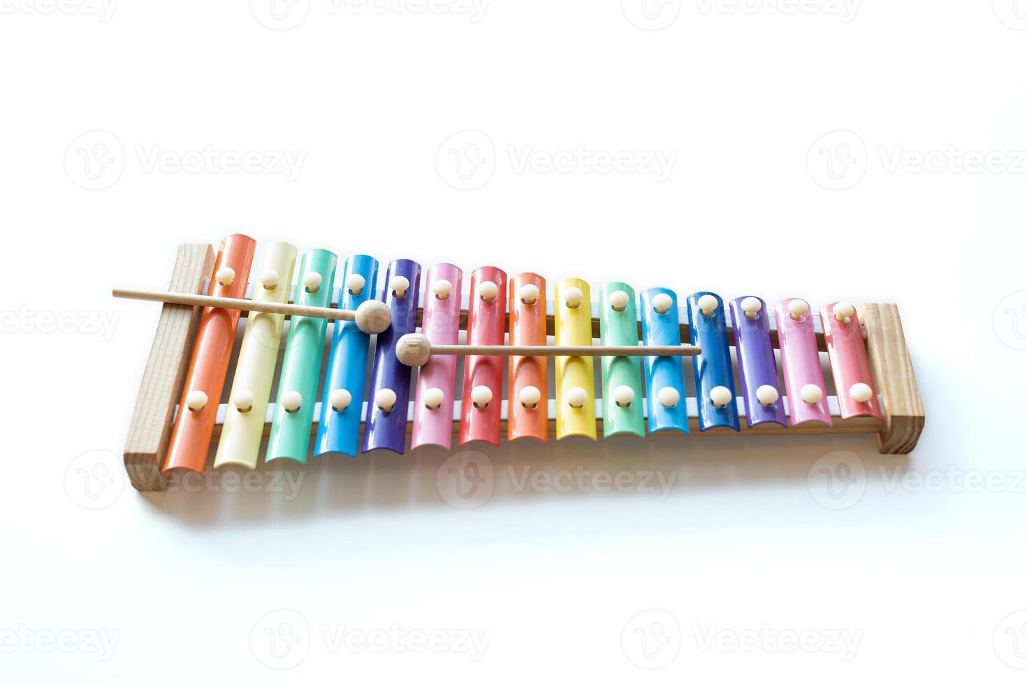 Two wooden sticks on colorful rainbow xylophone instrument toy isolated on white table background. photo