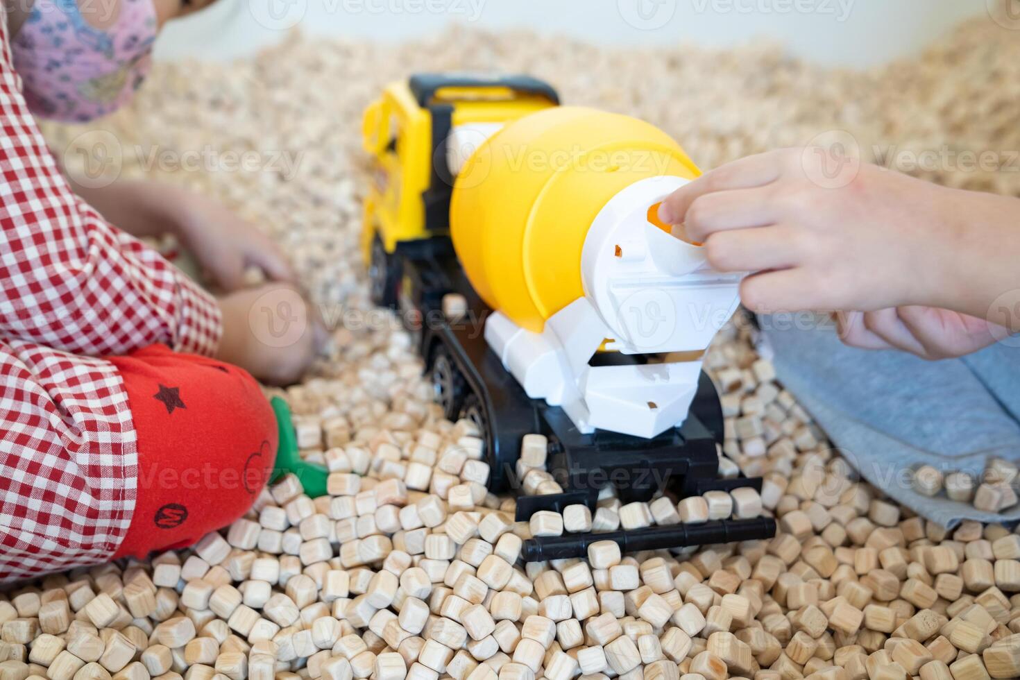 A kid is playing with a yellow plastic concrete mixer truck toy in the cork pool. photo