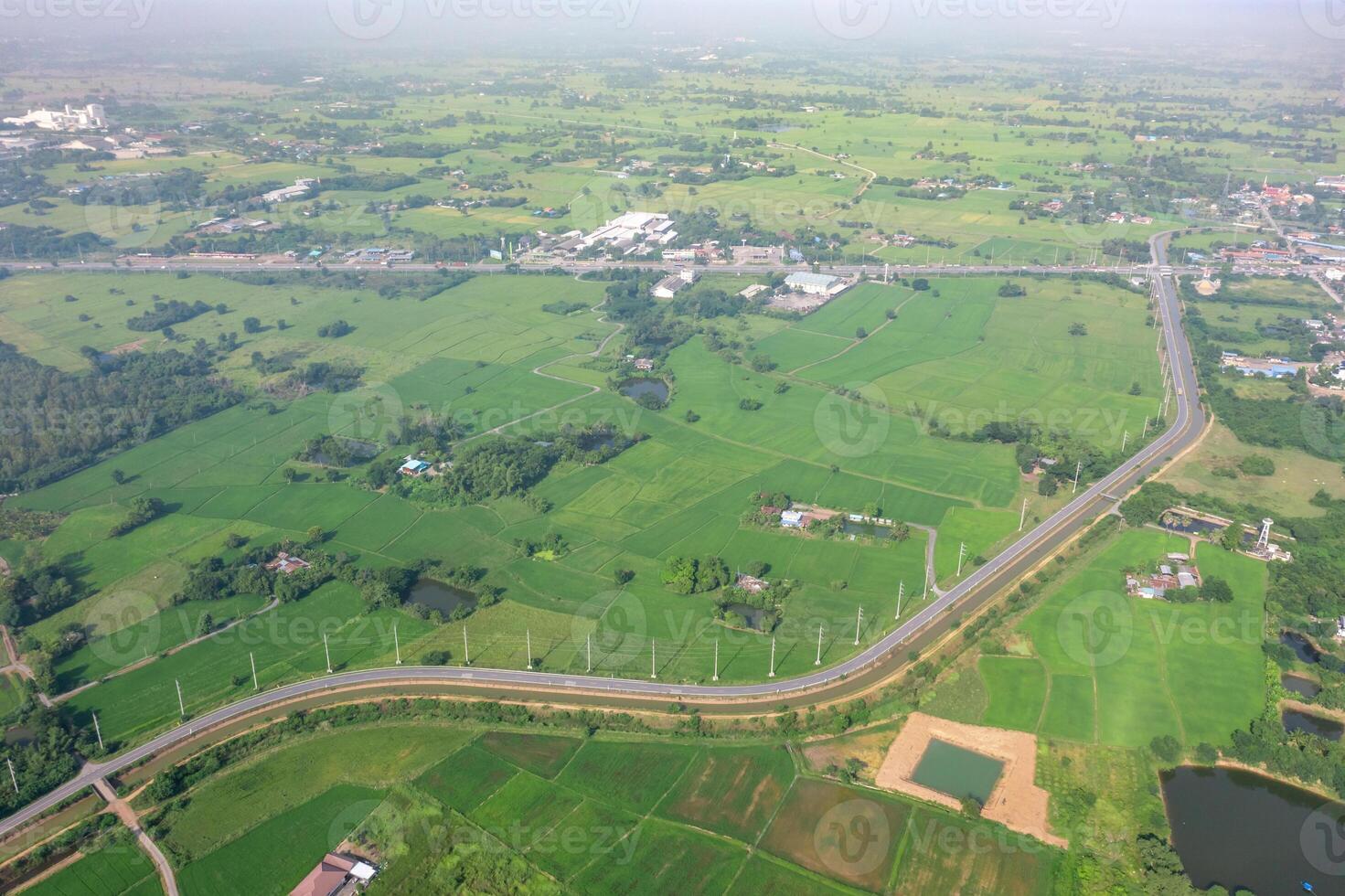 Drone view of Sufficiency Economy, Land full of agricultural activities with green rice fields, big ponds, and trees. Small houses and temple close by a pond. photo
