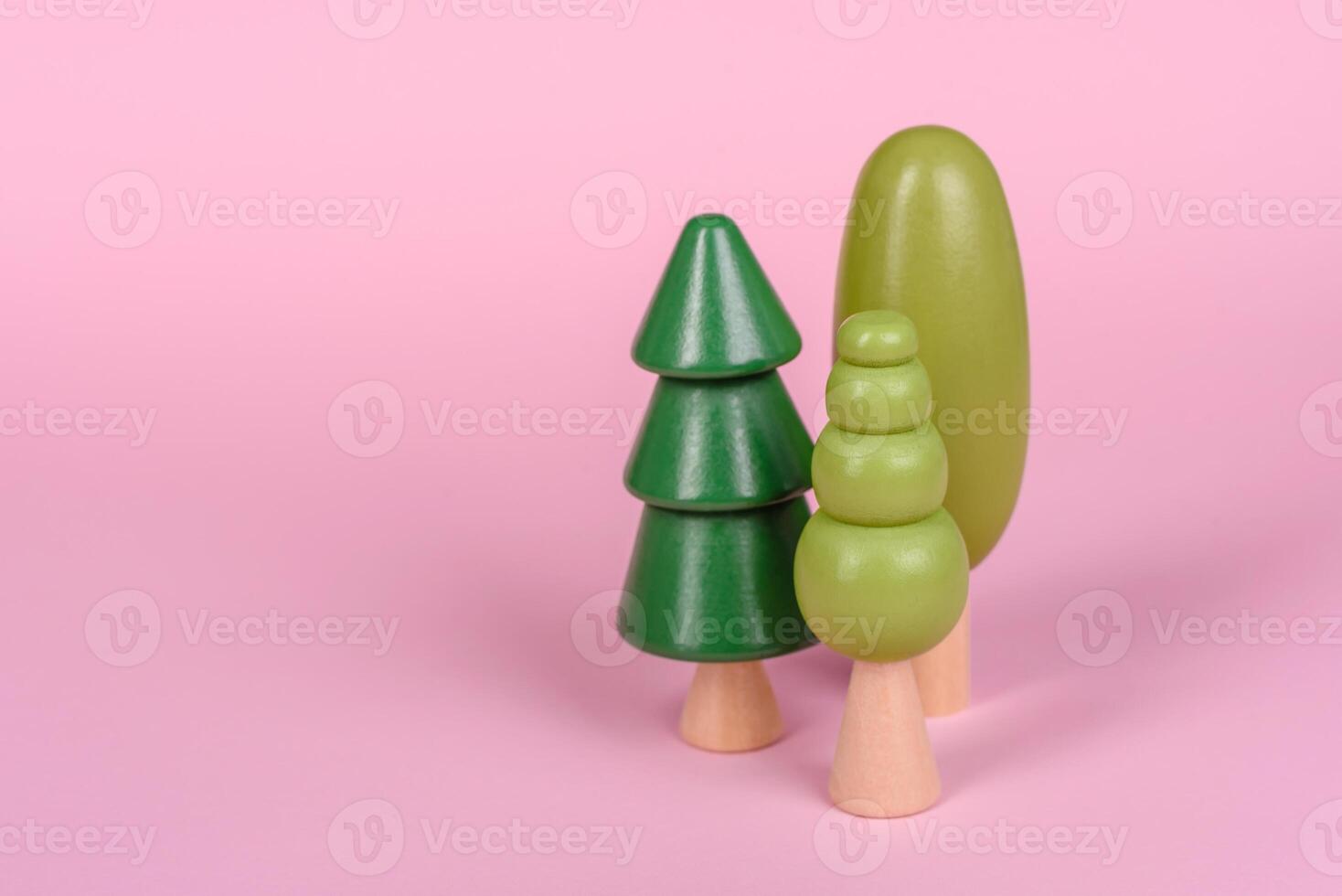 Wooden model of a tree with a green crown and trunk on a pink background photo