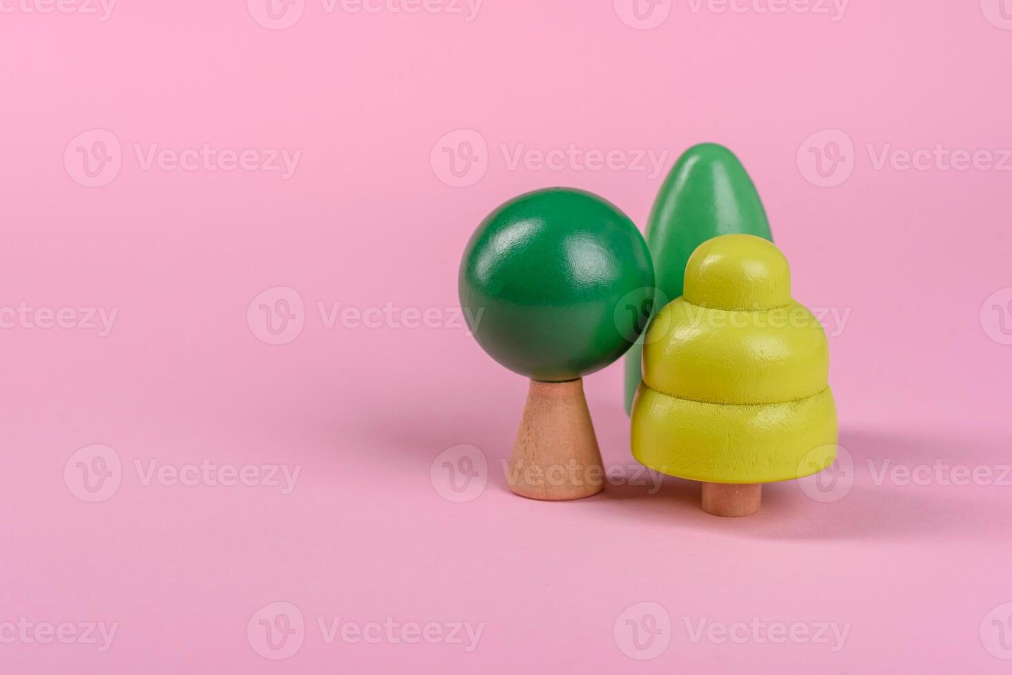 Wooden model of a tree with a green crown and trunk on a pink background photo