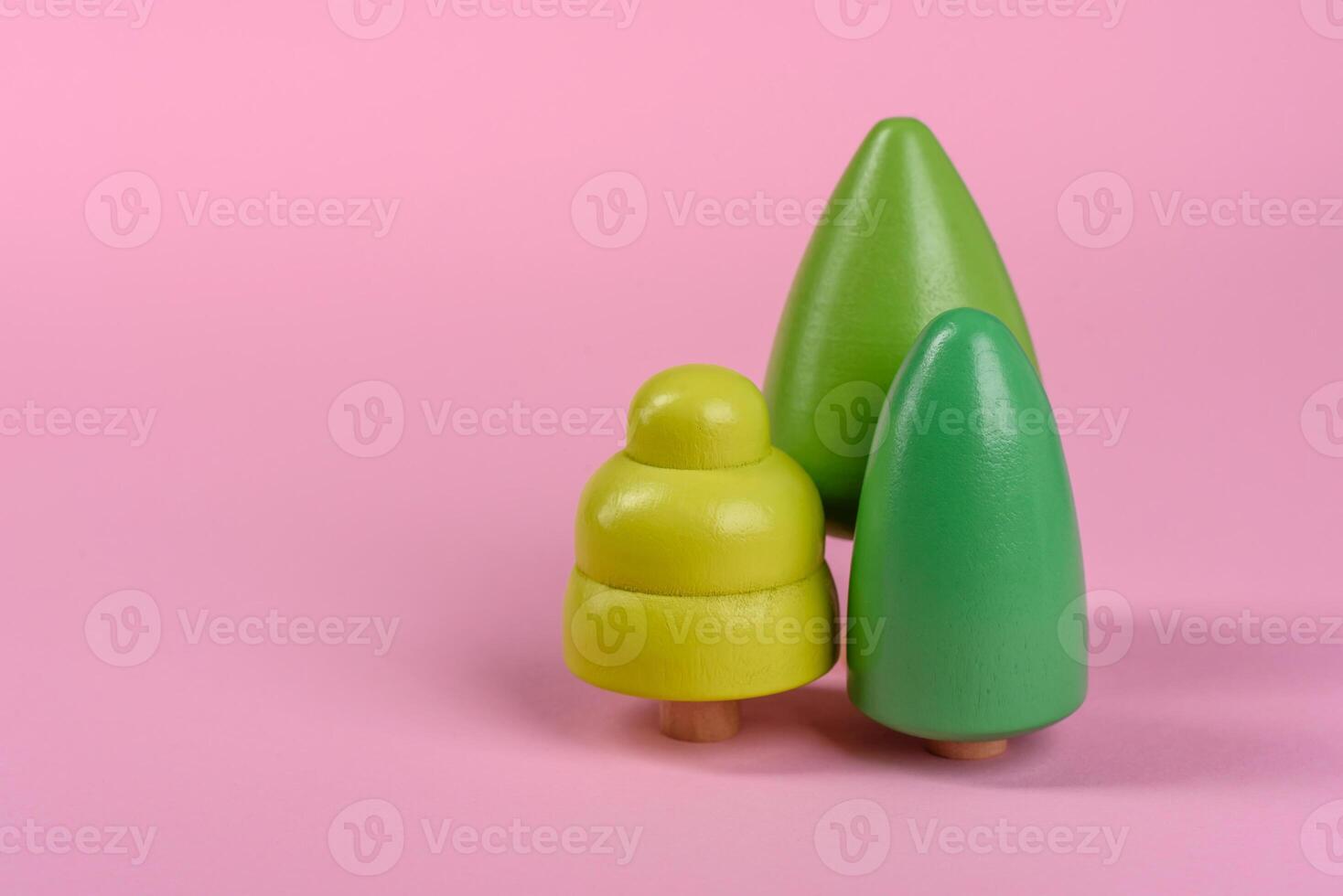 Wooden model of a tree with a green crown and trunk on a pink background photo