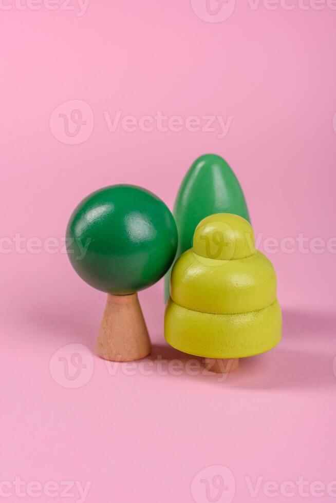 Wooden model of a tree with a green crown and trunk on a pink background photo
