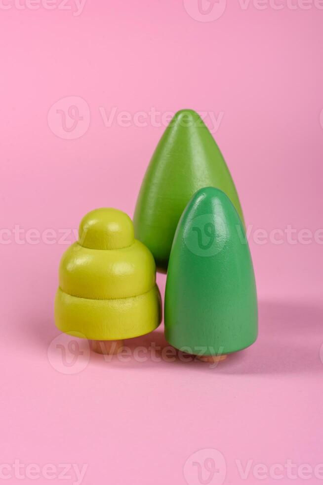 Wooden model of a tree with a green crown and trunk on a pink background photo