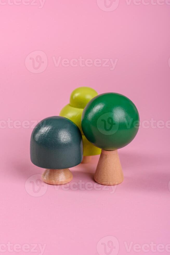 Wooden model of a tree with a green crown and trunk on a pink background photo