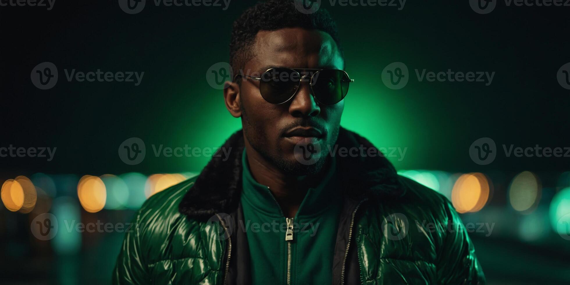 Dark-skinned guy in the green light He is wearing a black jacket and sunglasses. photo