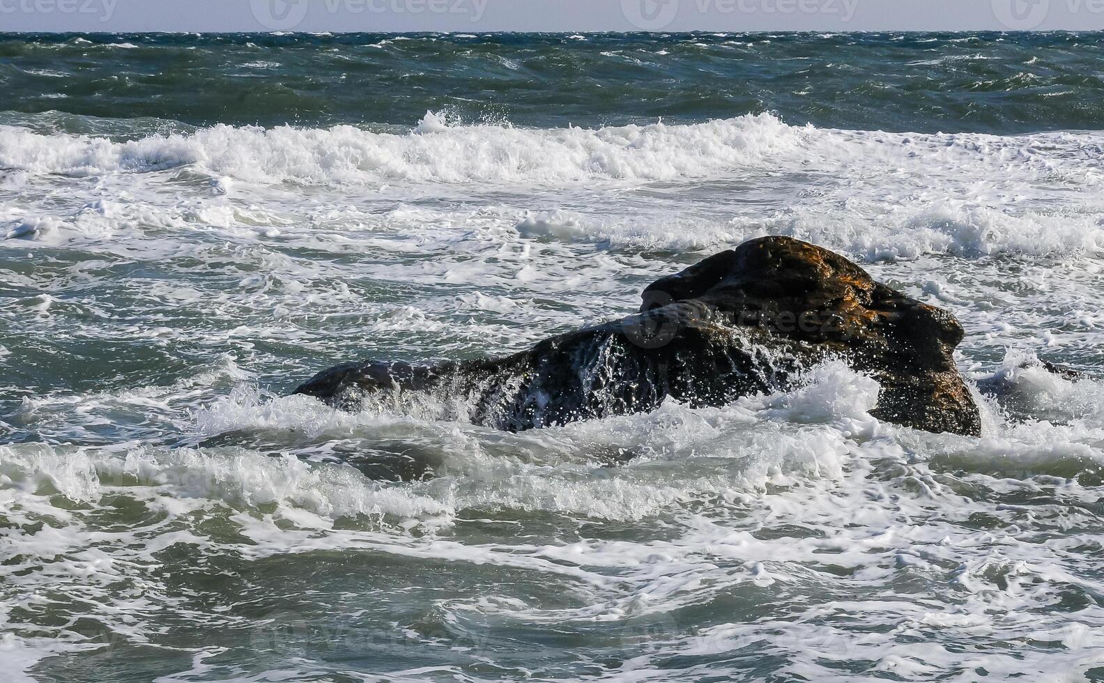 Waves break on a stone and white splashes of water fly into the air, Black Sea photo