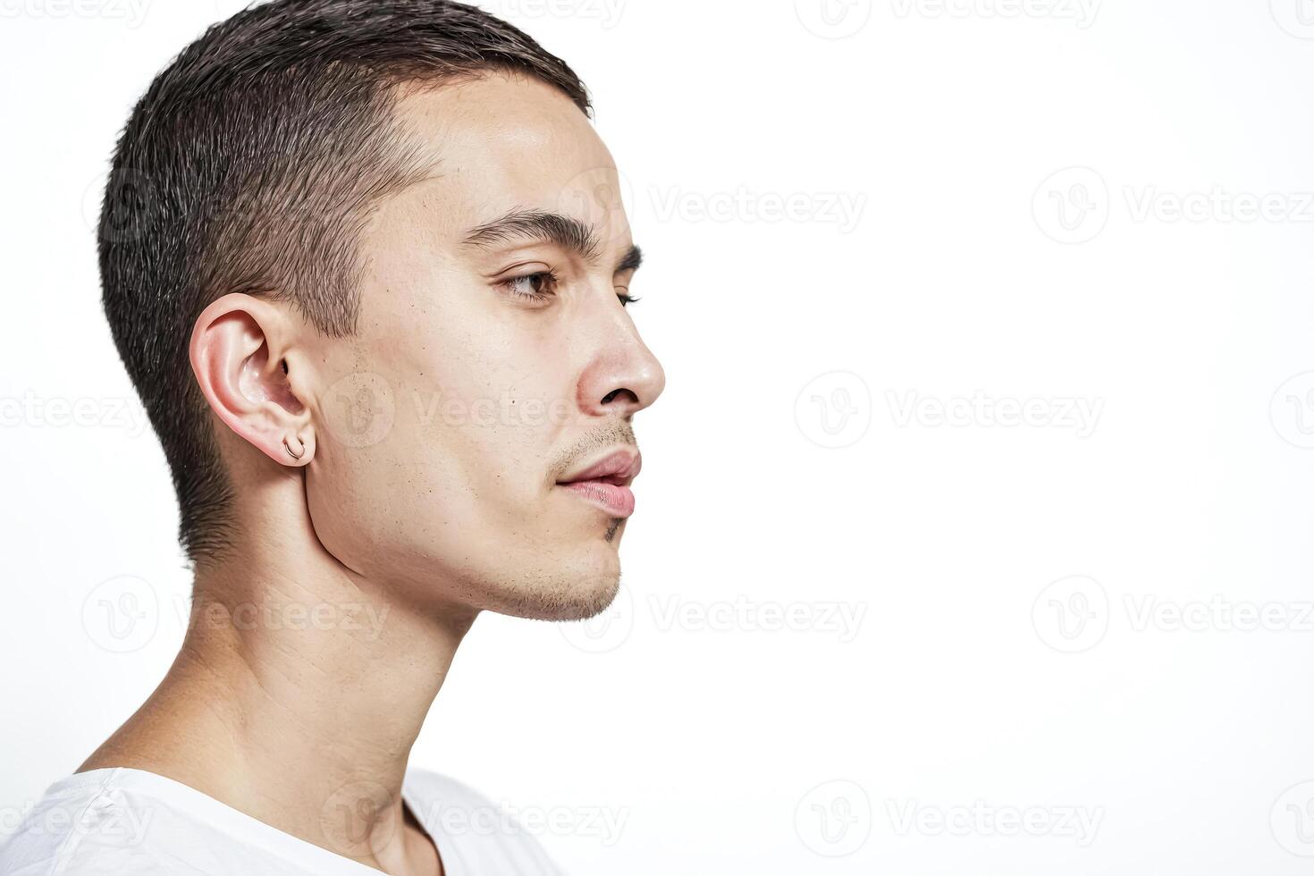 Young man with short hair and a piercing looking off to the side photo