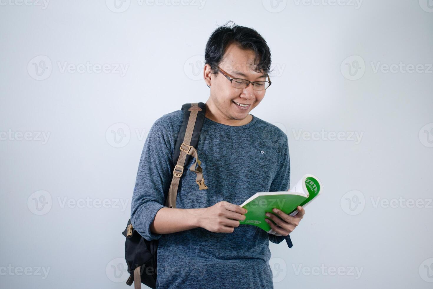 Asian young male student wearing bag and carrying books smiling and happy expression with isolated white background photo