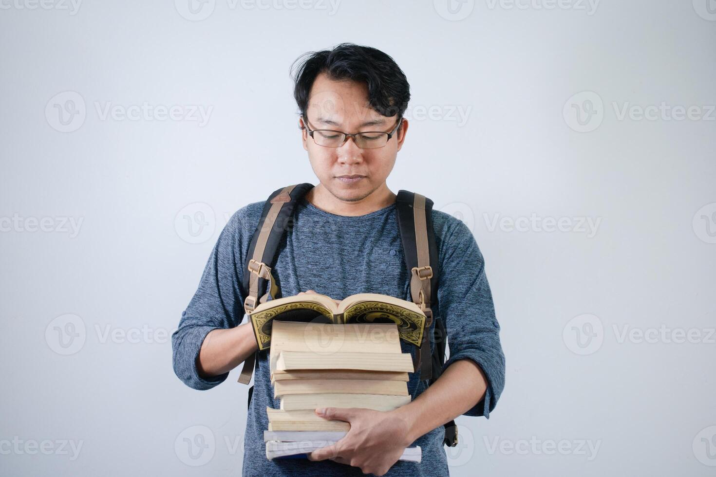 Asian young male student wearing bag and carrying a lot of books smiling and happy expression with isolated white background photo