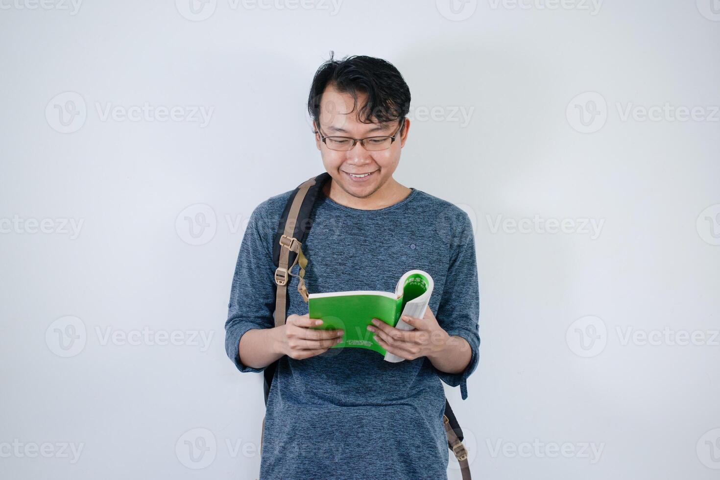 Asian young male student wearing bag and carrying books smiling and happy expression with isolated white background photo