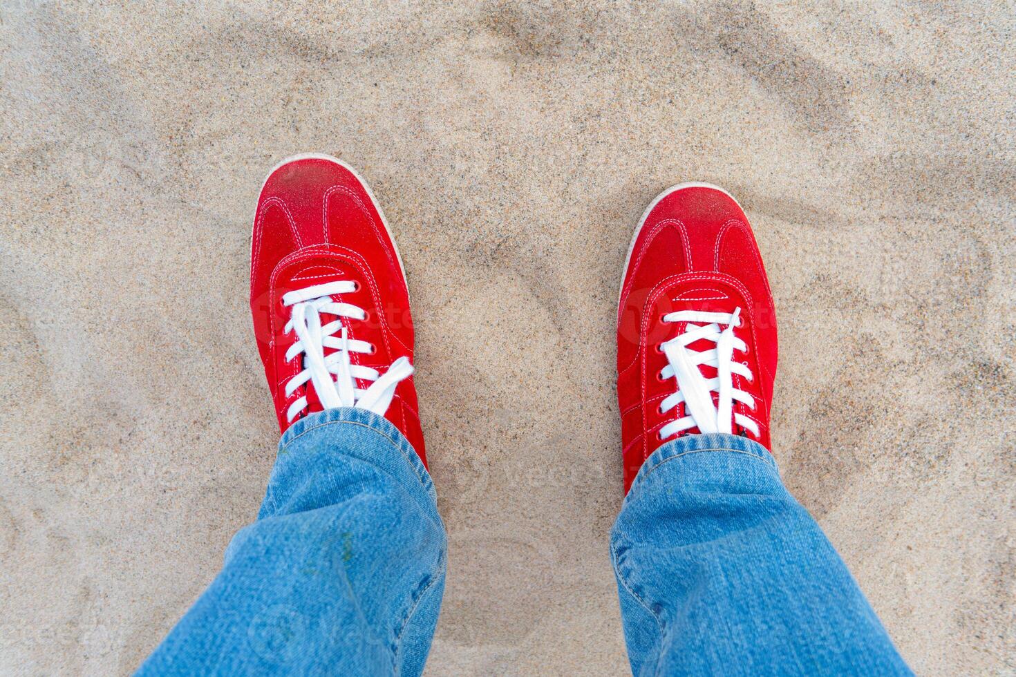 Red sneakers with white laces. Blue jeans. photo