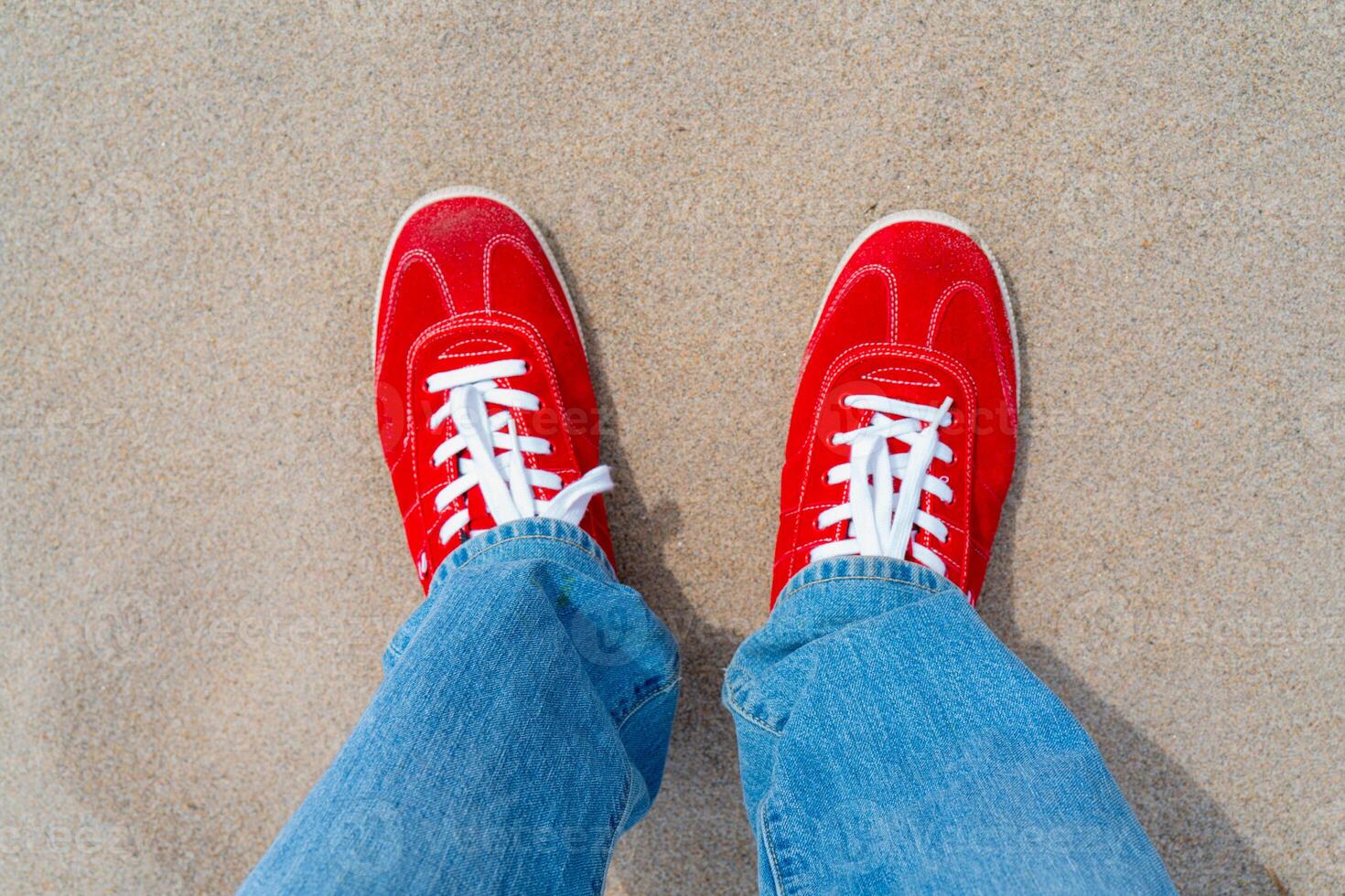 Red sneakers with white laces. Blue jeans. photo