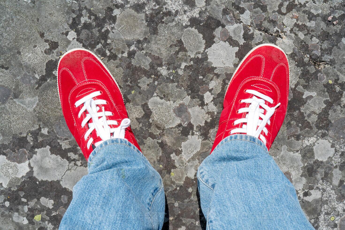 Red sneakers with white laces. Blue jeans. photo