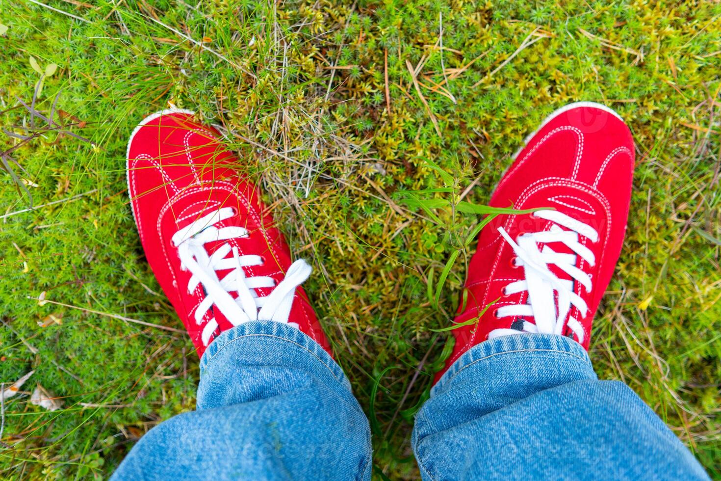 Red sneakers with white laces. Blue jeans. photo