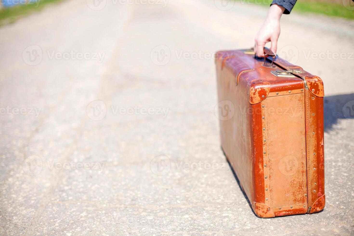 Old travel brown suitcase. Traveler stands on road. Single trip. photo