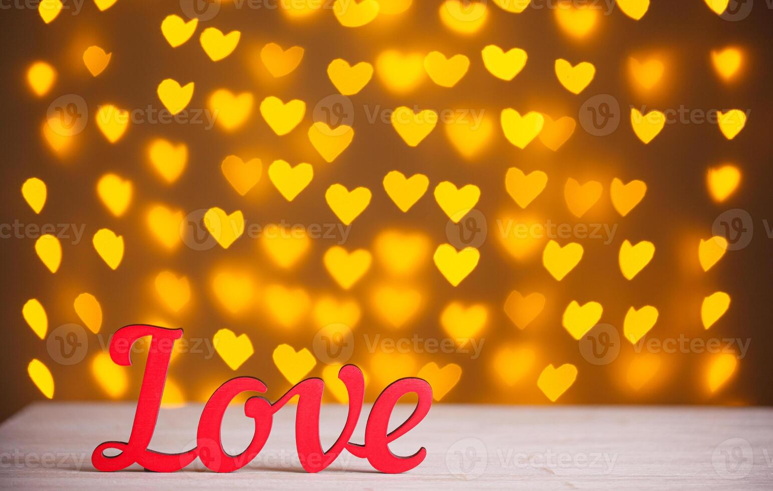the inscription Love on a wooden background with beautiful hearts made of lights on a blurred background photo