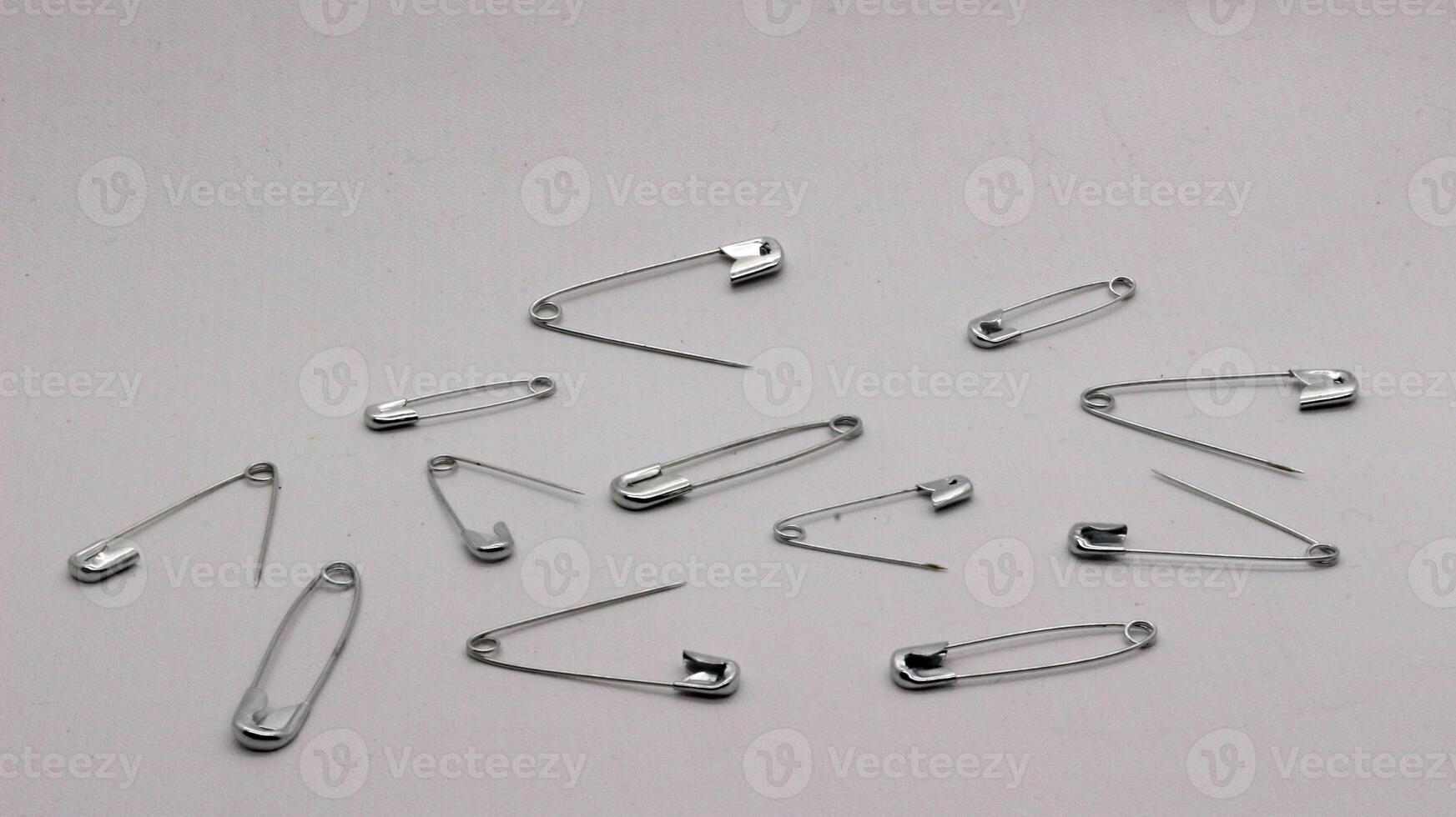 The safety pin is made of metal and silver in color. photo
