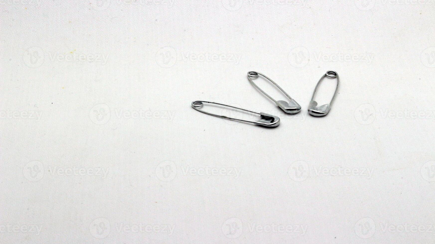 The safety pin is made of metal and silver in color. photo