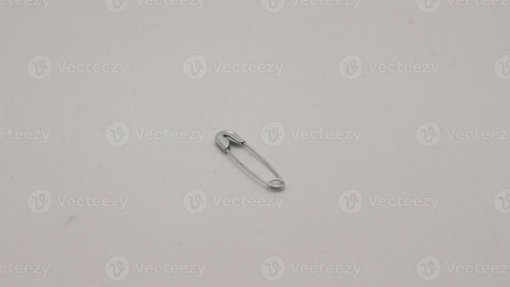 The safety pin is made of metal and silver in color. photo