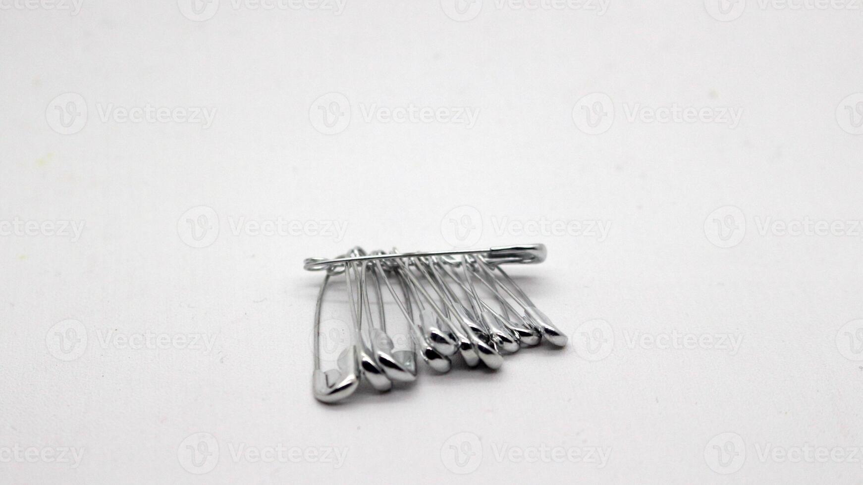 The safety pin is made of metal and silver in color. photo