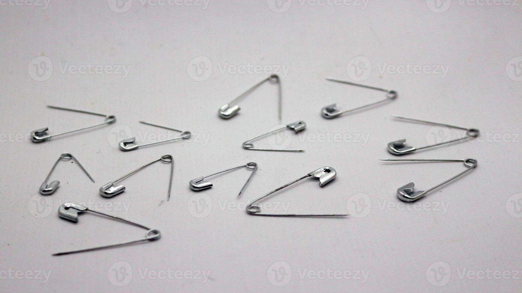 The safety pin is made of metal and silver in color. photo