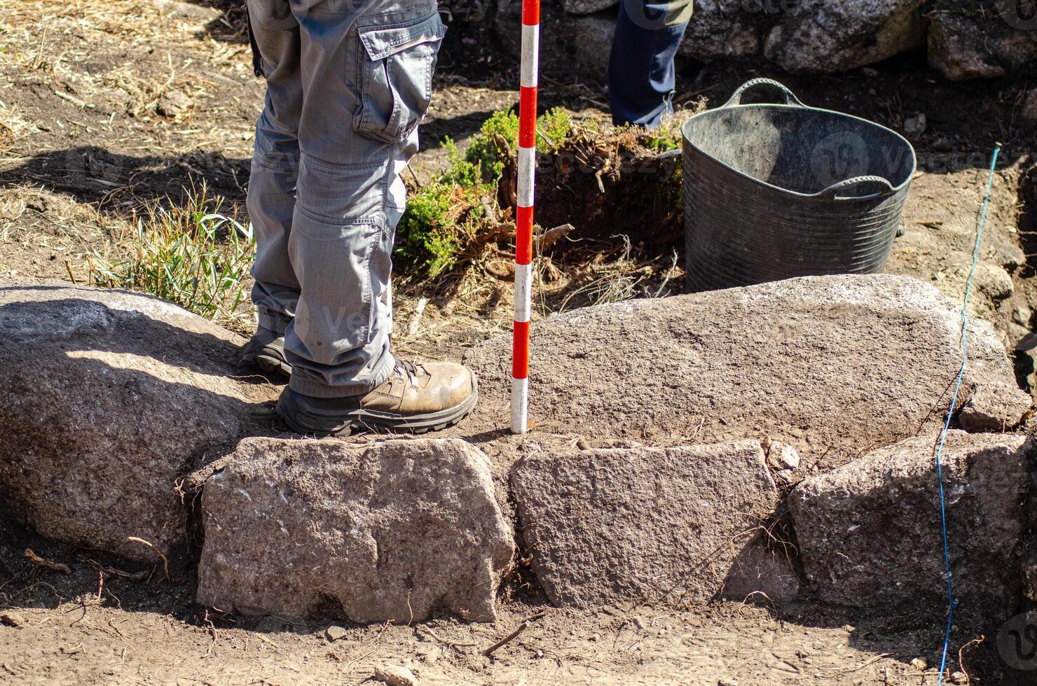 view of the legs of an archaeologist holding a range pole in an archaeological excavation. Archeology concept photo