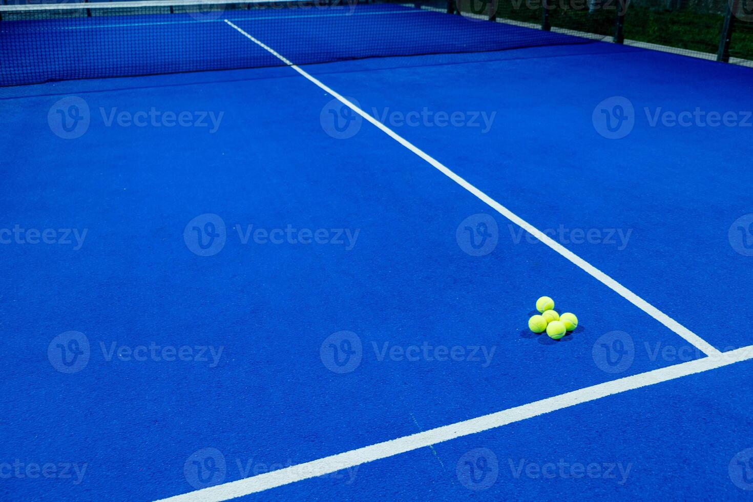balls on an empty paddle tennis court in the night photo