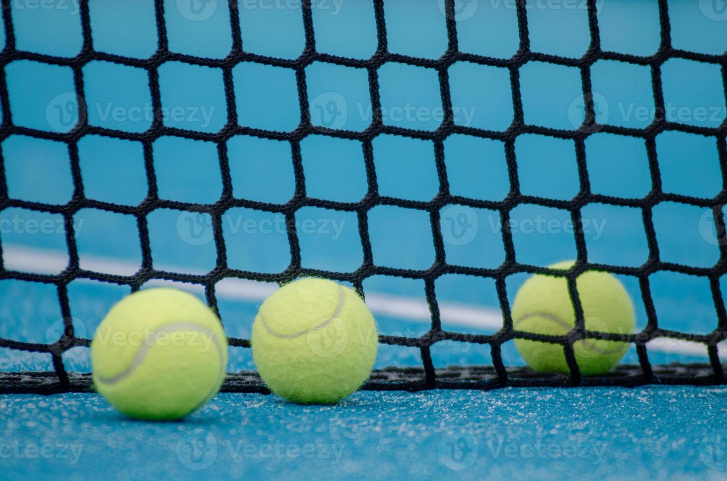 selective focus, three paddle tennis ball near the net in a blue paddle tennis court, racket sports concept photo