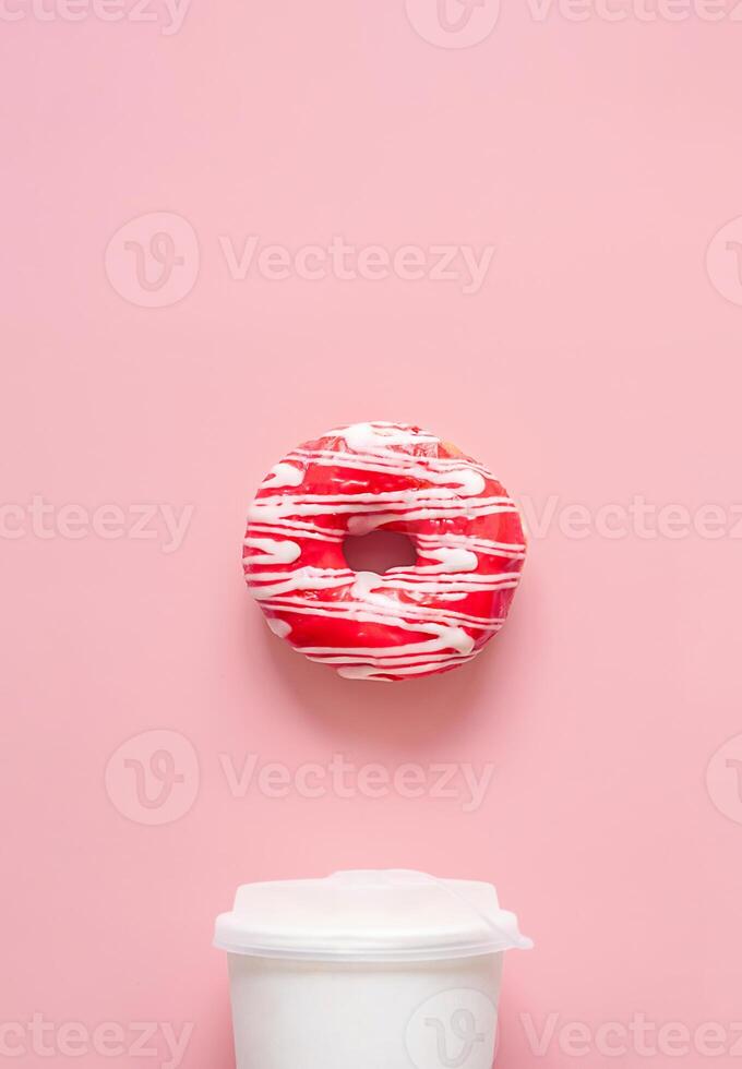 Pink frosted donut with white drizzle and white to go coffee cup. Breakfast or snack time concepts. photo