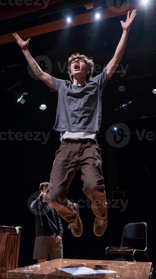 Young actor passionately rehearsing on stage, mid-air jump expression photo