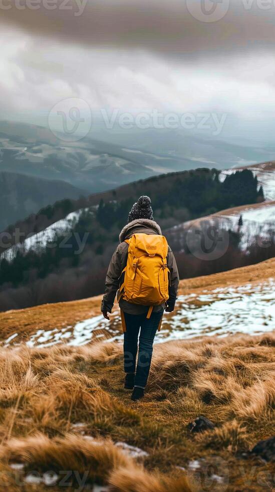Adventurer hiking in snowy mountains with yellow backpack photo