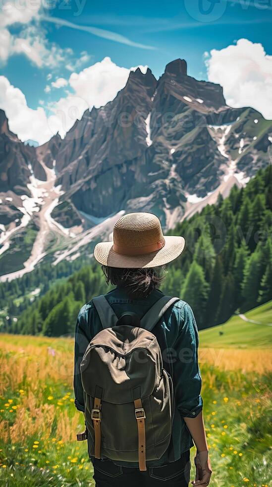 Hiker with backpack looking at mountain peaks in summer photo